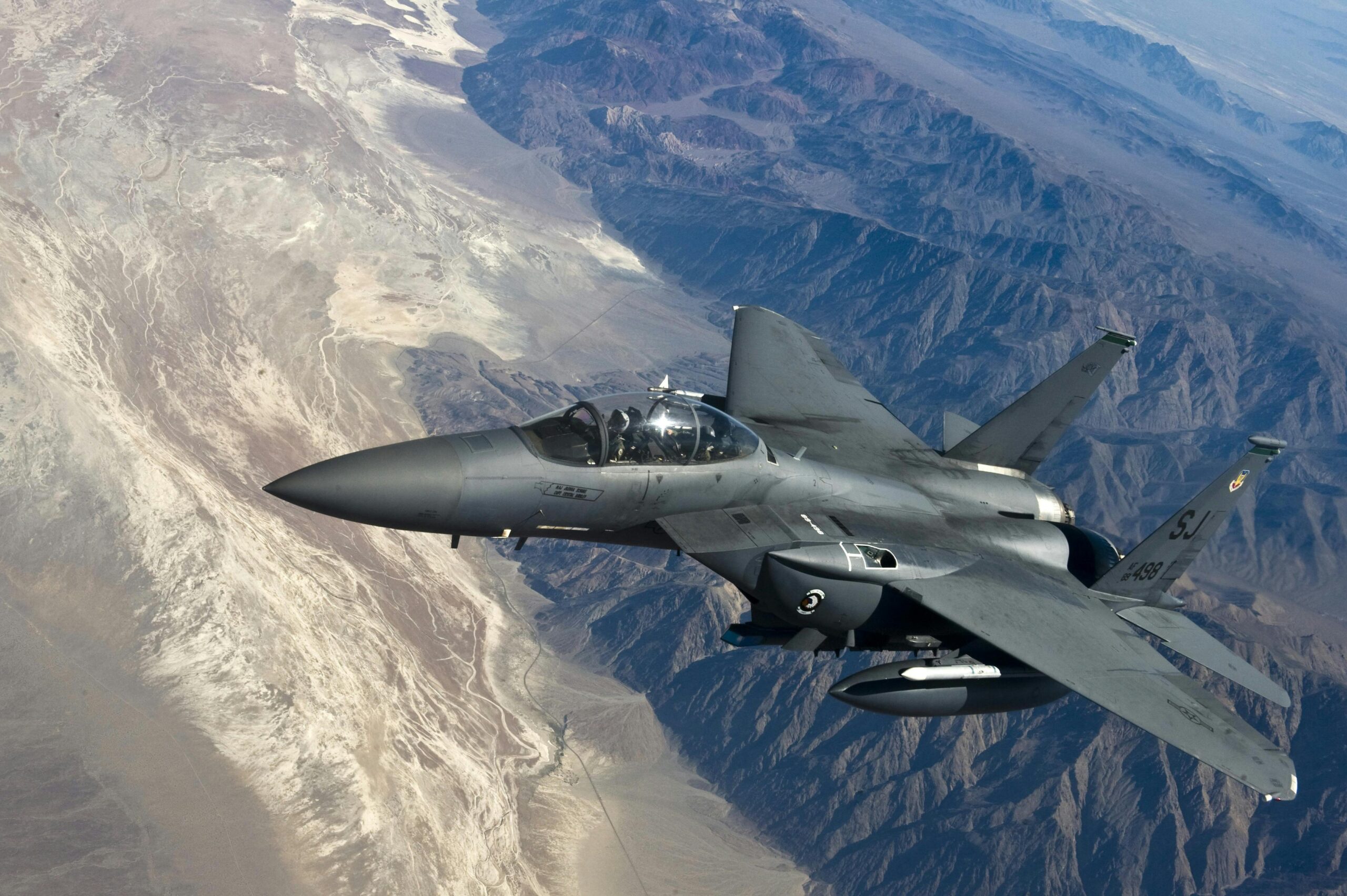 A military fighter jet flying above rugged mountain ranges, showcasing advanced aviation technology.